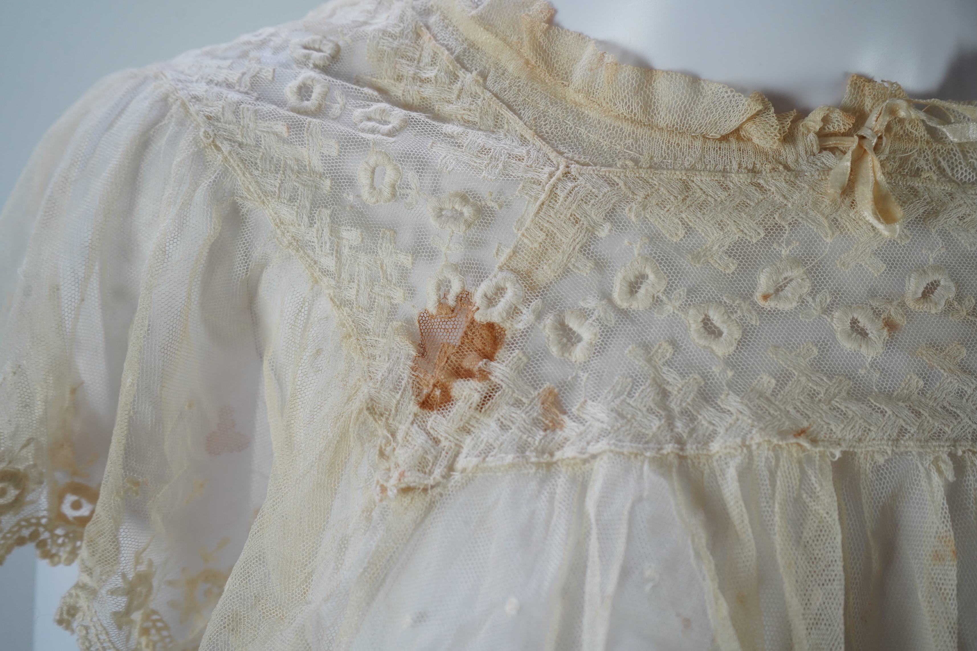 A suitcase containing a cream silk lace skirt to a dress, an Edwardian silk petticoat and various collars, possibly for theatrical use, silk petticoat 96 cm long. Condition - fair